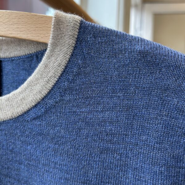 detalje Wat no. 3 Strik til kvinder - håndlavet i Italien Detail of blue short-sleeved knit blouse with light beige trim, Danish design.