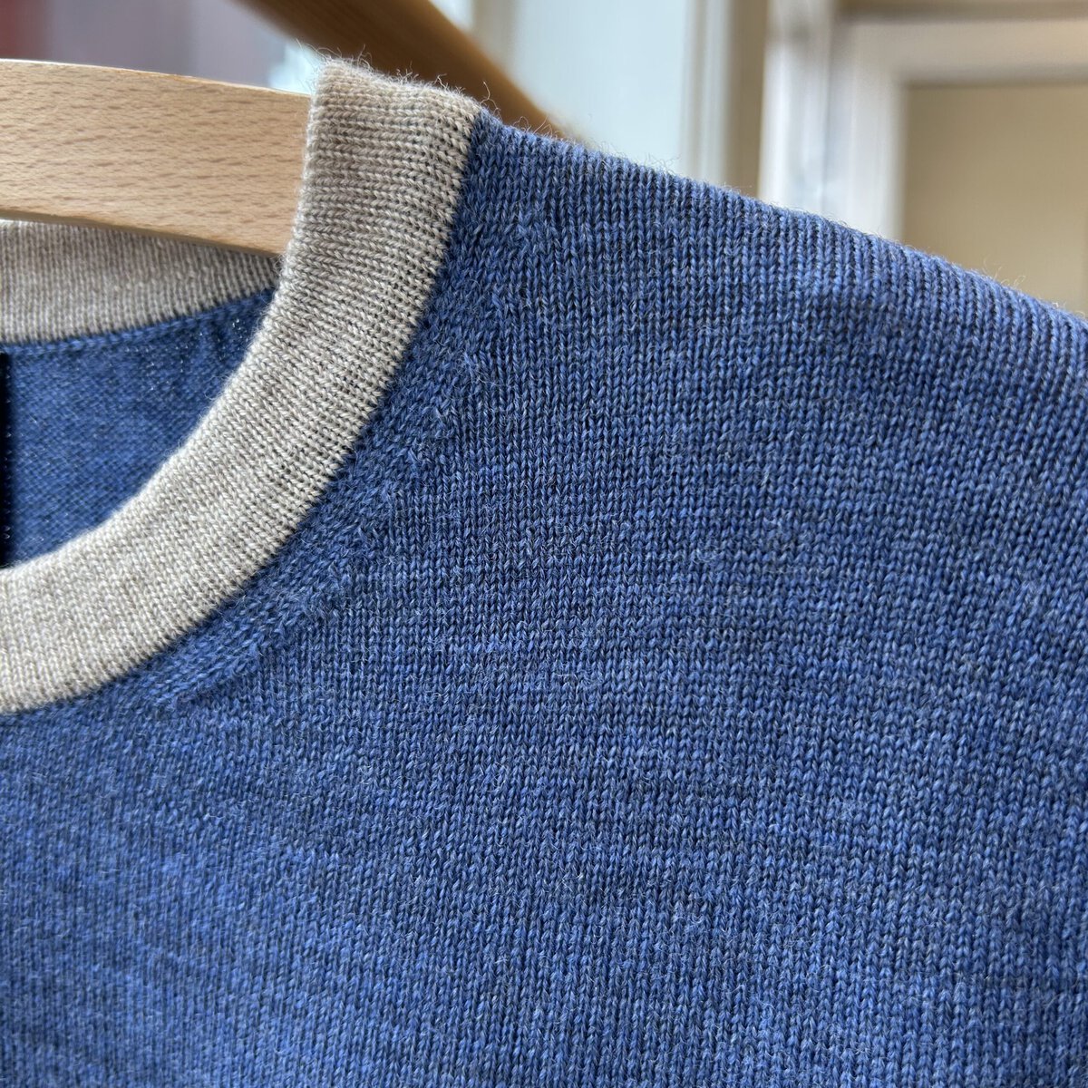 Detail of blue short-sleeved knit blouse with light beige trim, Danish design.